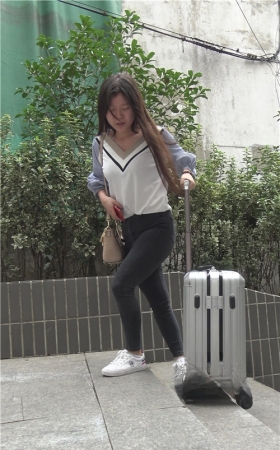 推着行李箱的黑色紧身牛仔裤女孩